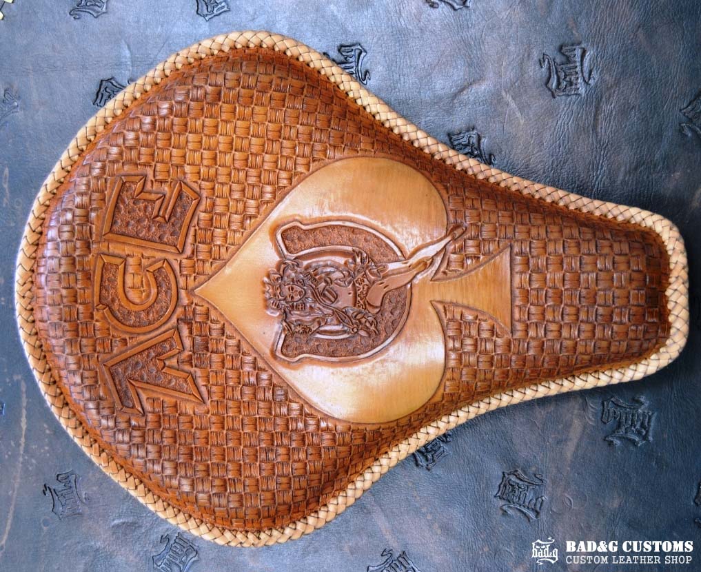"ACE Pin-Up Girl" design hand tooled and braided on a chopper solo seat. Veg tan leather with kangaroo lace.